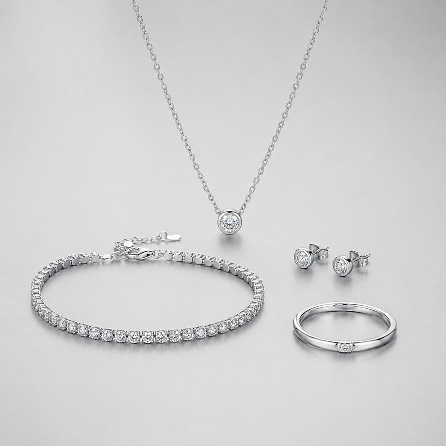Silver jewelry collection with necklace bracelet earrings and ring on soft gray background