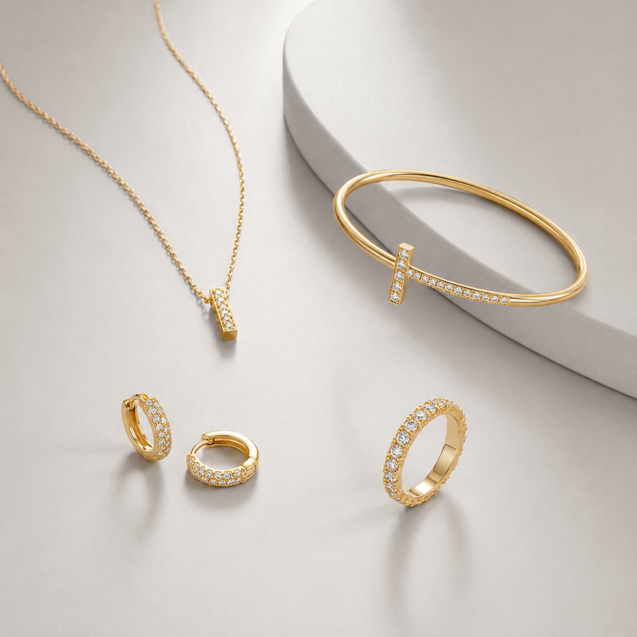 Gold jewelry collection with necklace bracelet earrings and ring on soft gray background