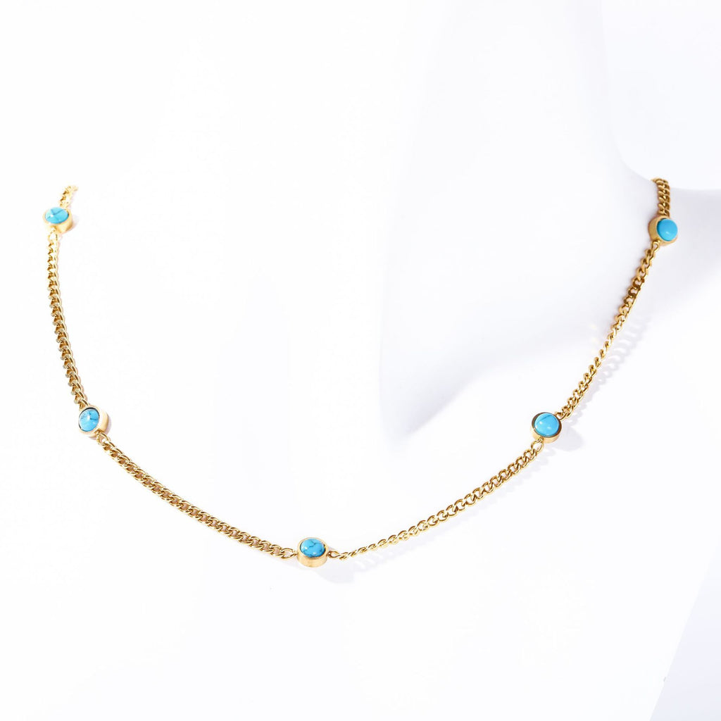 Gold electroplated turquoise necklace displayed on white fabric background