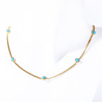 Gold electroplated turquoise necklace displayed on white fabric background