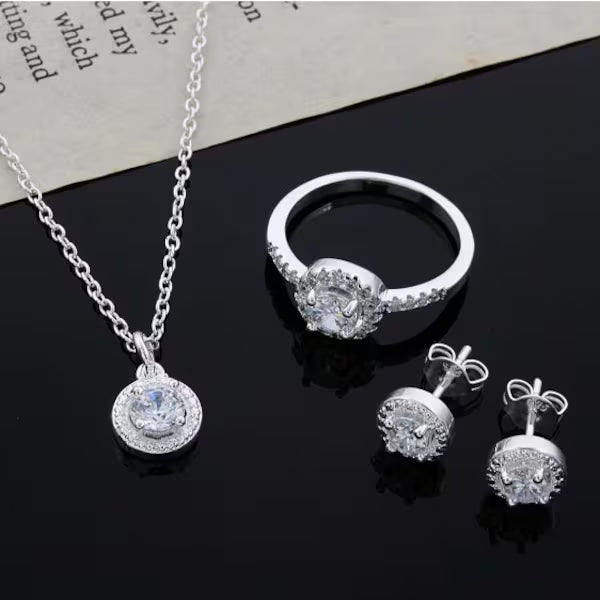 Silver necklace bracelet earrings and ring arranged on soft gray background