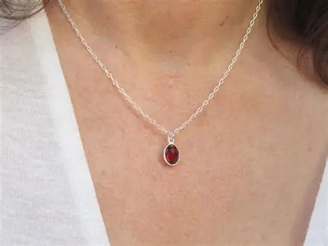 Close-up of silver garnet necklace with deep red garnet pendant in sterling silver