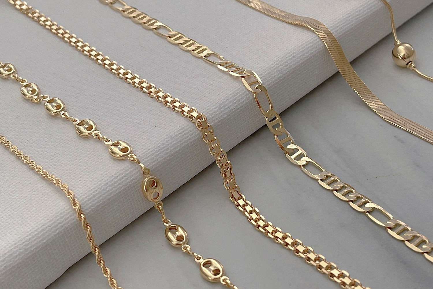 Elegant gold jewelry for women with necklace and bracelet on soft gray background
